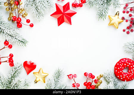 Weihnachten Hintergrund. Xmas Zusammensetzung Grenze mit schneebedeckten Tannen Zweig, rot Stechpalme Beeren, gold Sterne und Flitter. Weihnachten flach Draufsicht mit Kopie Raum Stockfoto