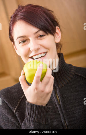 Junge Frau isst einen Apfel im Innenbereich Stockfoto
