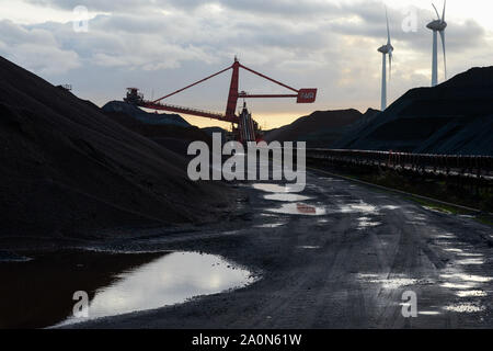 Deutschland, Hamburg, Hansaport Import von Kohle und Erz für Stahlwerke und Kohlekraftwerke, Lagerung in Kontrast mit Windenergieanlage im Hafen/Deutschland, Hamburg, Hansaport, Import von Kohle und Erz, Lagerung und Weitertransport zu Kraftwerken und Stahlwerken Stockfoto