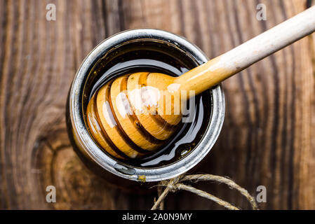 Glas Glas mit Honig und Pendelarm eingetaucht in Honig auf Holz- Hintergrund Stockfoto