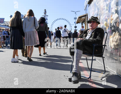 München, Deutschland. 21 Sep, 2019. Beginn des Oktoberfestes. Ein Eigentümer in der traditionellen Tracht sitzt neben seinem Andenken stand auf einem Stuhl. Das größte Volksfest der Welt dauert bis zum 6. Oktober. Quelle: Tobias Hase/dpa/Alamy leben Nachrichten Stockfoto