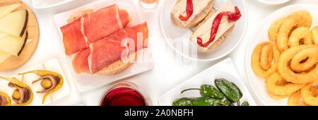 Ein Panorama von spanischen Tapas. Jamon, Tintenfischringe, Käse, gildas und andere Snacks, Schuß von oben auf weißem Hintergrund Stockfoto
