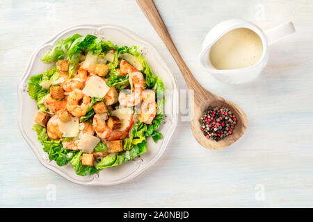 Garnelen Caesar Salat mit Parmesan Käse, Croutons und Salat, mit der Sauce in einer Soße Boot, Schuß von der Oberseite mit Pfefferkörnern Stockfoto