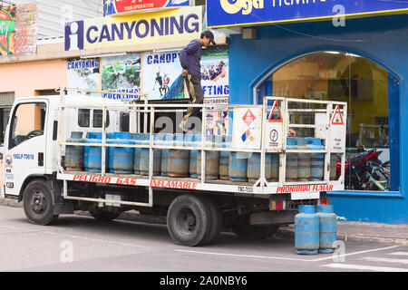 BANOS, Ecuador - 28. FEBRUAR 2014: Nicht identifizierte Person auf einem Lkw voll Gas Flaschen auf der 16 de November Straße in Baños, Ecuador Stockfoto