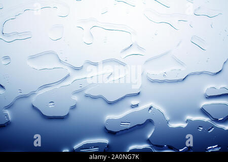 Verschüttetes Wasser auf Glas Spiegel Oberfläche, abstrakten Hintergrund, nasse Textur gradient Muster in blauer Farbe, Design Wasser blots Ansicht schließen top Nach oben Stockfoto