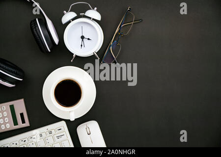 Büro Business Objects von weißen Kaffeetasse, Tastatur, Kopfhörer, Weiß Wecker, Taschenrechner, Maus und Brille auf der Tafel. Stockfoto