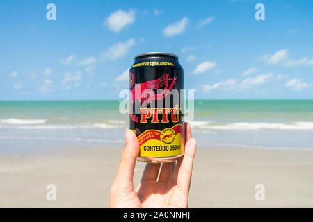 Ilha de Itamaraca, Brasilien - ca. August 2019: Hand mit einem PITU können am Strand - Pitu ist ein alkoholisches Getränk (destilliertem Alkohol) aus C-Zucker Stockfoto