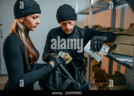 Räuber in schwarzen Uniform stiehlt Geld aus dem Speicherort Stockfoto