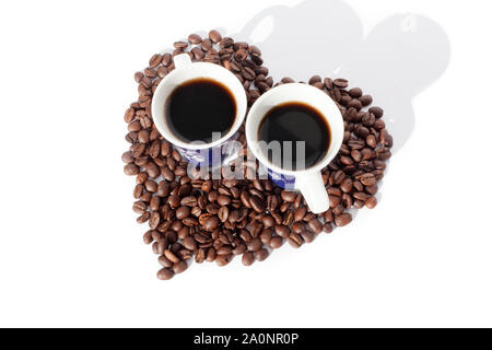 Zwei Tassen schwarzen Kaffee und ein Herz aus Kaffeebohnen auf weißem backgroung isoliert, Ansicht von oben Stockfoto