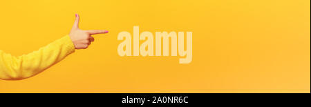 Woman's Hand weist mit dem Finger auf etwas, auf gelben Hintergrund, Panoramablick Mock-up-Bild Stockfoto