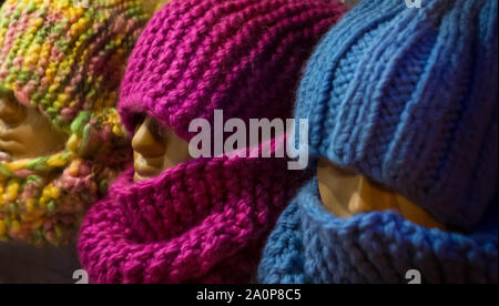 Mehrfarbige gestrickte Mützen und Schals auf schaufensterpuppen. Weiche und bequeme Kleidung. Stockfoto