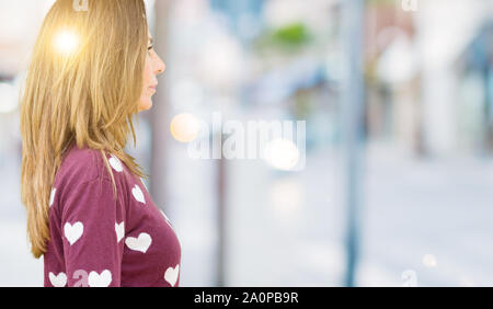 Schönen mittleren Alter Frau mit Herz Pullover über isolierte Hintergrund auf der Suche nach Side, entspannen Profil mit natürliches Gesicht mit selbstbewussten Lächeln darstellen. Stockfoto