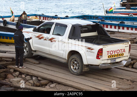 TIQUINA, BOLIVIEN - Oktober 16, 2014: Toyota Pickup Truck fahren auf einen Holz- Fähre an der Straße von Tiquina am Titicaca-See in Tiquina, Bolivien Stockfoto