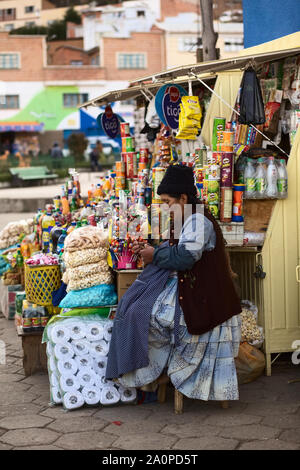 TIQUINA, BOLIVIEN - Oktober 16, 2014: Nicht identifizierte Frau an einem Snack Stand sitzen und tun Häkeln auf dem Hauptplatz von San Pedro de Tiquina, Bolivien Stockfoto