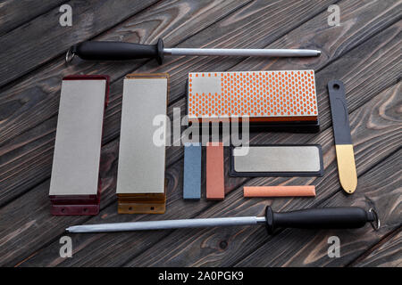 Eine Vielzahl von Messer Spitzer. Schleifsteine und Geräte auf einem Holz- Hintergrund. Schleifen der Steine Stockfoto