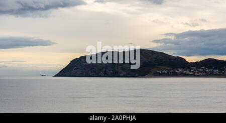 Ein Frachtschiff navigiert um Great Orme Landspitze in Llandudno an der Küste von North Wales. Stockfoto