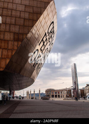 Cardiff, Wales, UK - 17. März 2013: Die markante moderne Architektur von Cardiff Millennium Center Theater dominiert Roald Dahl Plas in der Stadt" Stockfoto