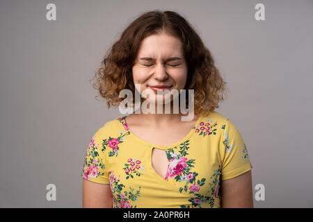 Wunderschöne Frau mit geschlossenen Augen. Blumiges Kleid. Porträt einer gut aussehenden Frau. Stockfoto