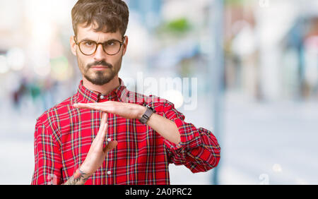 Jungen gutaussehenden Mann Brille über isolierte Hintergrund tun time out Geste mit den Händen, frustriert und ernstes Gesicht Stockfoto
