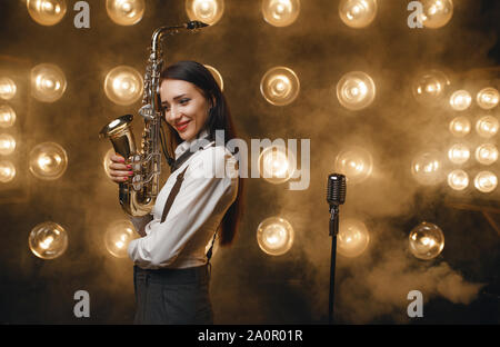 Weibliche saxophonist wirft mit Saxophon auf der Bühne Stockfoto