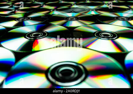 CDs/DVDs liegen auf einem schwarzen Hintergrund mit bunten Lichtreflexe. Stockfoto