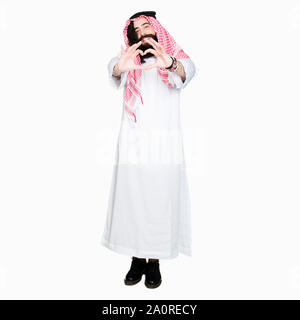 Arabian Business Mann mit langem Haar zu tragen traditionelle Kufiya Schal in der Liebe mit Herz und mit Hand lächelnd. Romantische Konzept. Stockfoto
