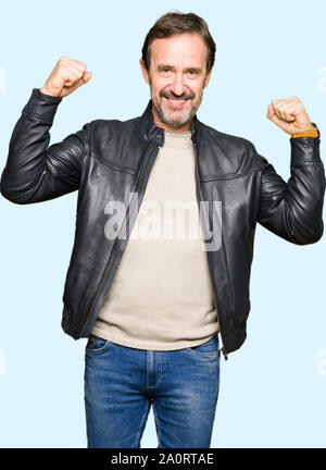 Mittleres Alter stattlicher Mann mit schwarzen Lederjacke, die Arme Muskeln lächelte stolz. Fitness Concept. Stockfoto