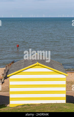 Farbenfrohe Strand Hütten in der Nähe von Whitstable an der Küste von Kent im Spätsommer mit Offshore- Windenergieanlagen im Hintergrund Stockfoto