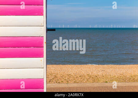 Farbenfrohe Strand Hütten in der Nähe von Whitstable an der Küste von Kent im Spätsommer mit Offshore- Windenergieanlagen im Hintergrund Stockfoto