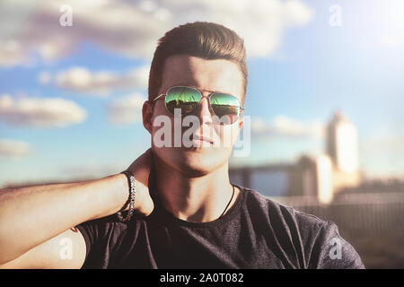 Porträt einer stattlichen stilvolle Kerl in der Sonnenbrille, die draußen wirft Stockfoto