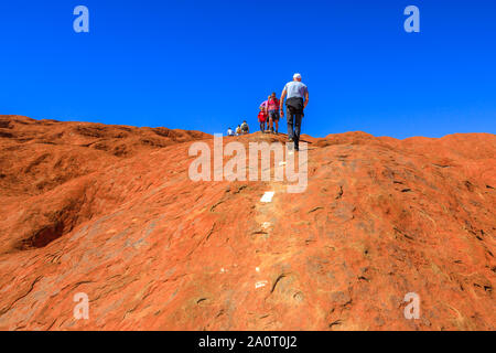 Uluru, Northern Territory, Australien - 23.August 2019: Menschen Abstieg entlang der lackiert Leitlinien über die Oberseite des Ayers Rock in den Uluru-Kata Tjuta National Stockfoto