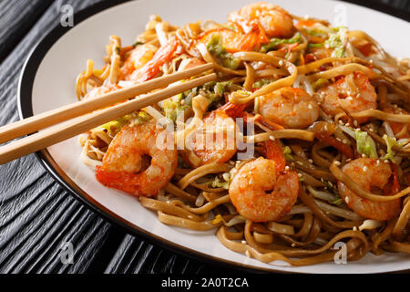 Chinesisches Essen Chow Mein Nudeln mit Garnelen, Gemüse und Sesamsamen close-up auf einem Teller auf den Tisch. Horizontale Stockfoto