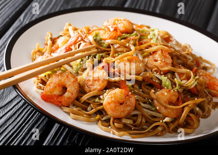 Rühren gebratene Chow Mein Nudeln mit Garnelen, Gemüse und Sesamsamen close-up auf einem Teller auf den Tisch. Horizontale Stockfoto