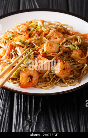 Servieren von Chow Mein Nudeln mit Garnelen und Gemüse close-up auf einem Teller auf den Tisch. Vertikale Stockfoto