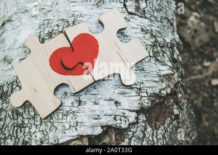 Rotes Herz ist auf die Stücke der Holzpuzzle nebeneinander liegend auf Holz- Hintergrund dargestellt. Liebe Konzept. St. Valentinstag