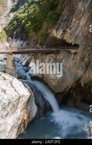 Strom Wasser über die Kante, unter Fußgängerbrücke ein Wasserfall entlang Marble canyons an baiyang Trail, Taroko Nationalpark, Taiwan fließt Stockfoto