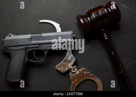 Pistole, Handschellen und schwarzen Hammer auf schwarzem Hintergrund isoliert. Recht und Gesetz Konzept Stockfoto