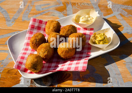 Weiße Platte mit bitterballen (traditionelle niederländische Fleisch Kugeln), Mayonaise und Senf auf der sonnenbeschienenen Holztisch Stockfoto