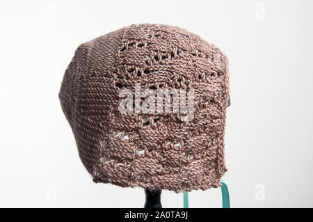 Handknit baby Haube isoliert Fiber arts Lace baby Hut in der Farbe taupe mit Aqua Band, auf weißem Hintergrund. Stockfoto