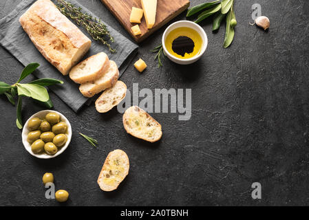 Ciabatta. Frische italienische Ciabatta Brot mit Kräutern, Olivenöl, Parmesan und Oliven auf schwarzem Hintergrund, Ansicht von oben, kopieren. Italienisches Essen. Stockfoto