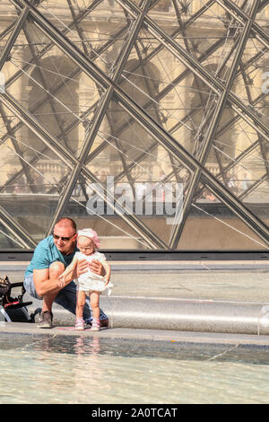 Ein Vater hält seine Baby Mädchen vor Wasser Brunnen im Louvre, Paris, Frankreich Stockfoto