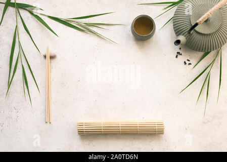 Asiatische Lebensmittel Hintergrund - grüner Tee, Teekanne und Essstäbchen aus Bambus matte und Blätter auf weißem Hintergrund, kopieren. Asiatische, chinesische japane Stockfoto