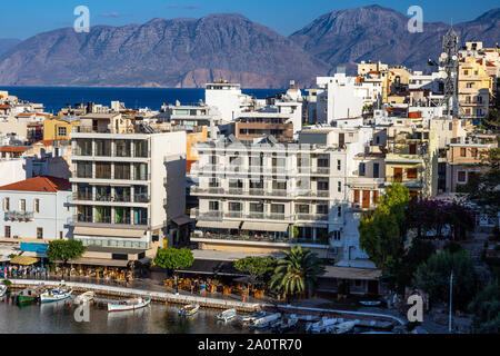 AGIOS NIKOLAOS, KRETA, GRIECHENLAND: 12. September 2019: See Voulismeni und verschiedenen bunten Gebäude in Agios Nikolaos bei Sonnenuntergang gesehen, Osten der Insel Kreta, Griechenland Stockfoto