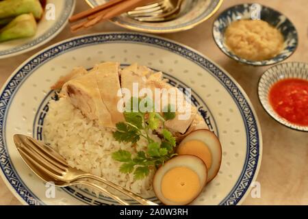 Hainanese Chicken Rice. Duftreis in Hühnerbrühe gekocht; Dann garniert mit pochiertem Huhn und Ei. Stockfoto