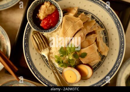 Hainanese Chicken Rice. Duftreis in Hühnerbrühe gekocht; Dann garniert mit pochiertem Huhn und Ei. Stockfoto