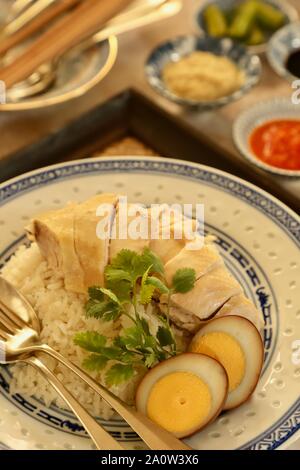 Hainanese Chicken Rice. Duftreis in Hühnerbrühe gekocht; Dann garniert mit pochiertem Huhn und Ei. Stockfoto