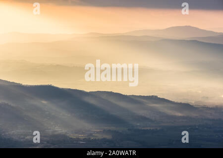 Sonnenstrahlen kommen über ein Tal in Umbrien (Italien) mit schönen goldenen Stunden Farben. Stockfoto