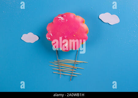Pink cookie als airballoon auf blauem Hintergrund Stockfoto