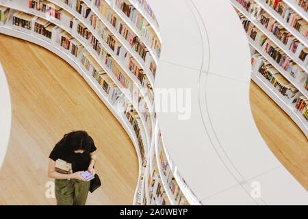 Ein Buch geliebten Spaziergänge durch Bücherregale in der Bibliothek in Singapur. Es wird gesagt, dass ÒWhenever sie ein gutes Buch lesen, irgendwo auf der Welt eine Tür öffnen Stockfoto