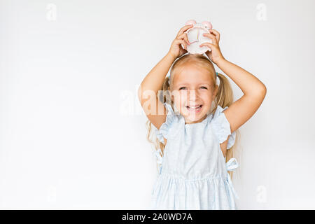 Adorable Little girl Holding Wecker, kopieren. Zicklein stehend auf weißen Hintergrund. Zeit für die Schule, Promotion, Verkauf. Aufgeregt Mädchen am Morgen Stockfoto